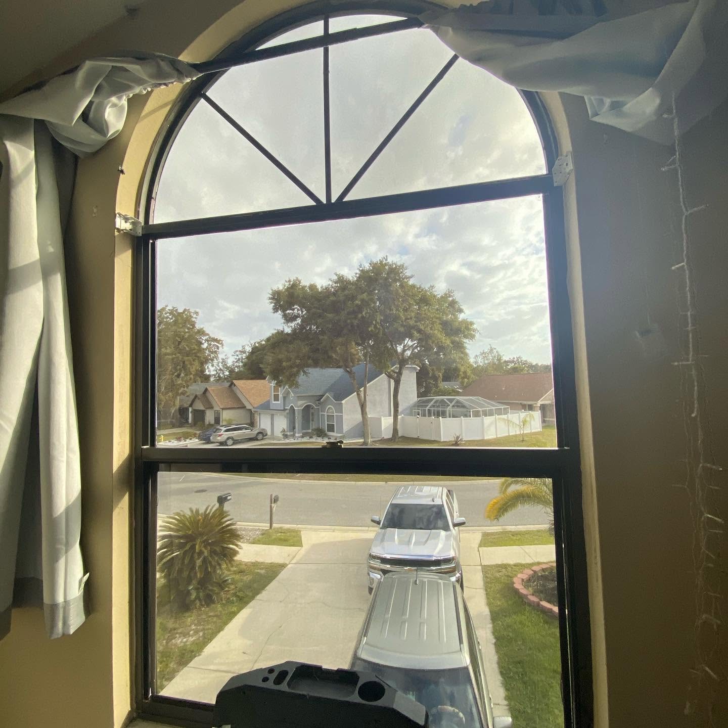 Arched residential window with tint installed, view from inside the home